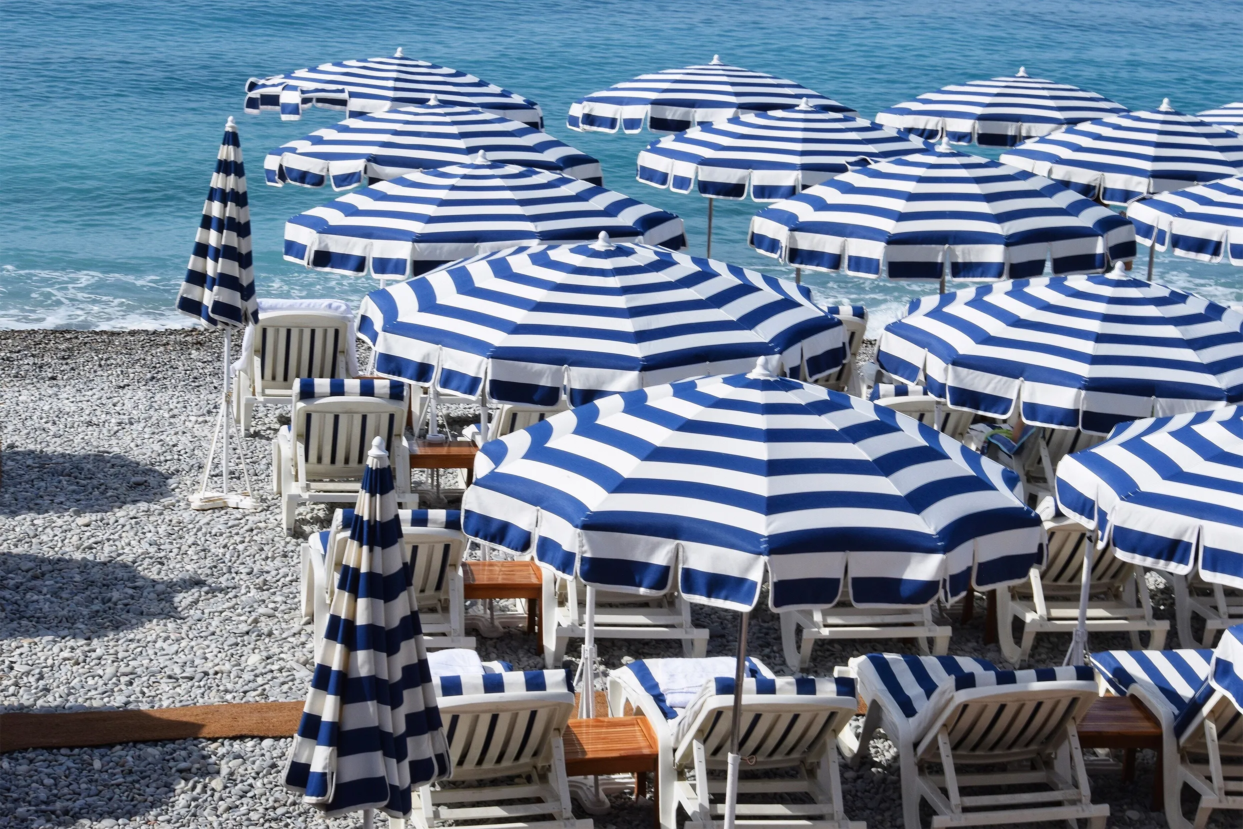 Ombrelloni a righe bianche e blu su una spiaggia di ciottoli
