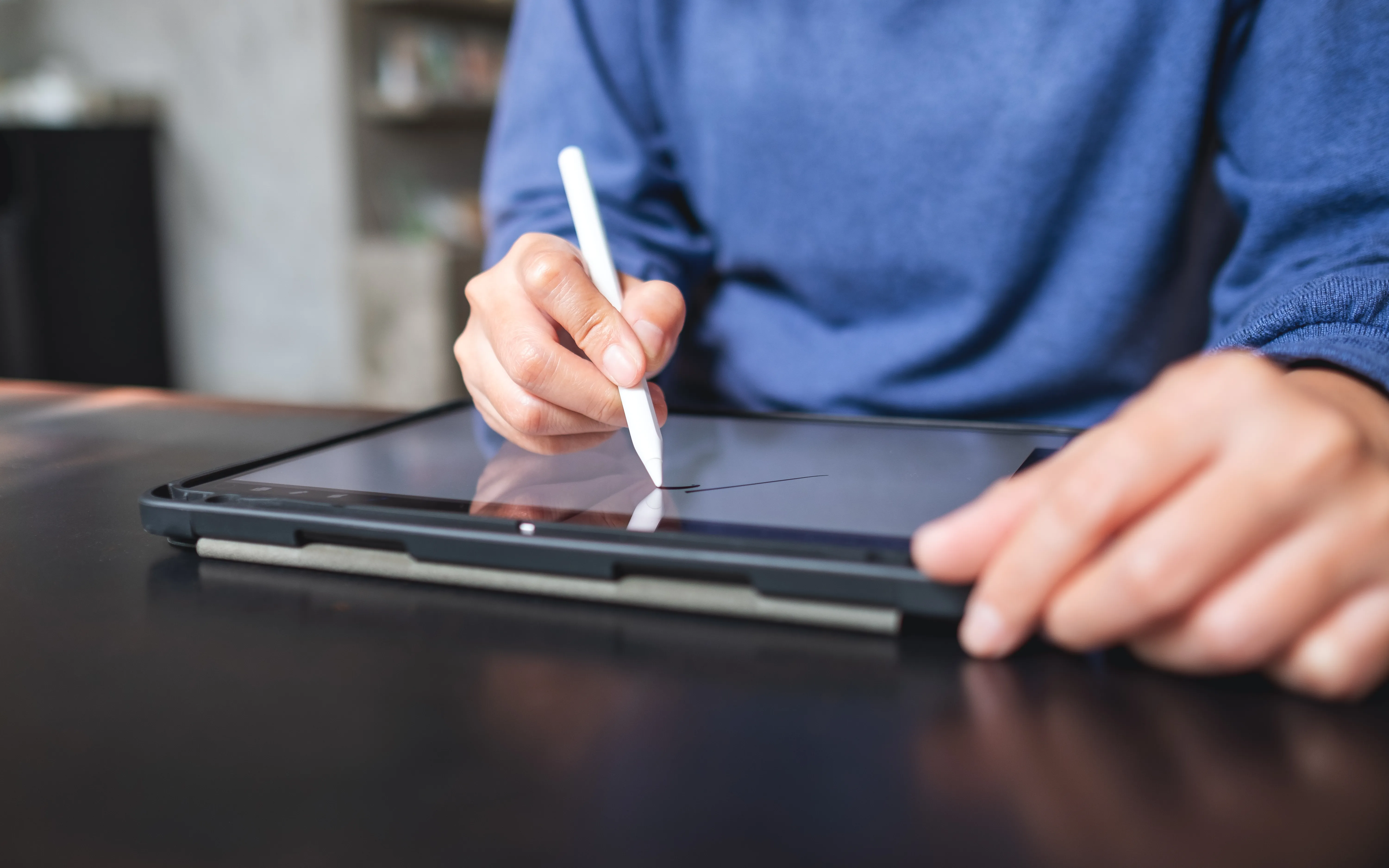 Mano che firma con una penna digitale su un tablet