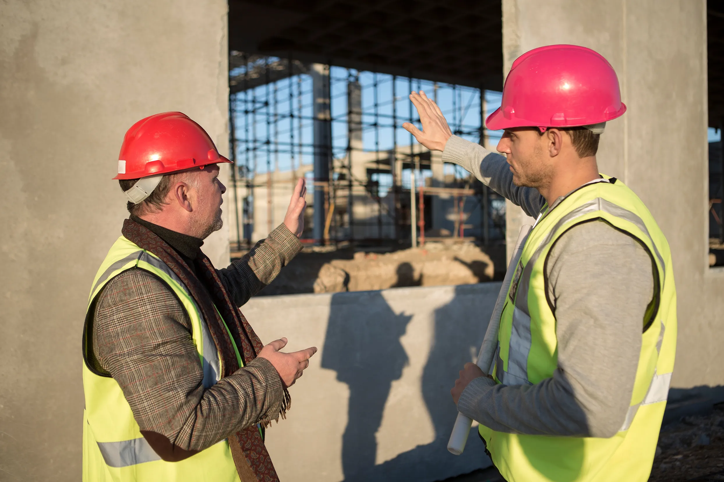 Due tecnici con caschetto e gilet ad alta visibilità in un cantiere
