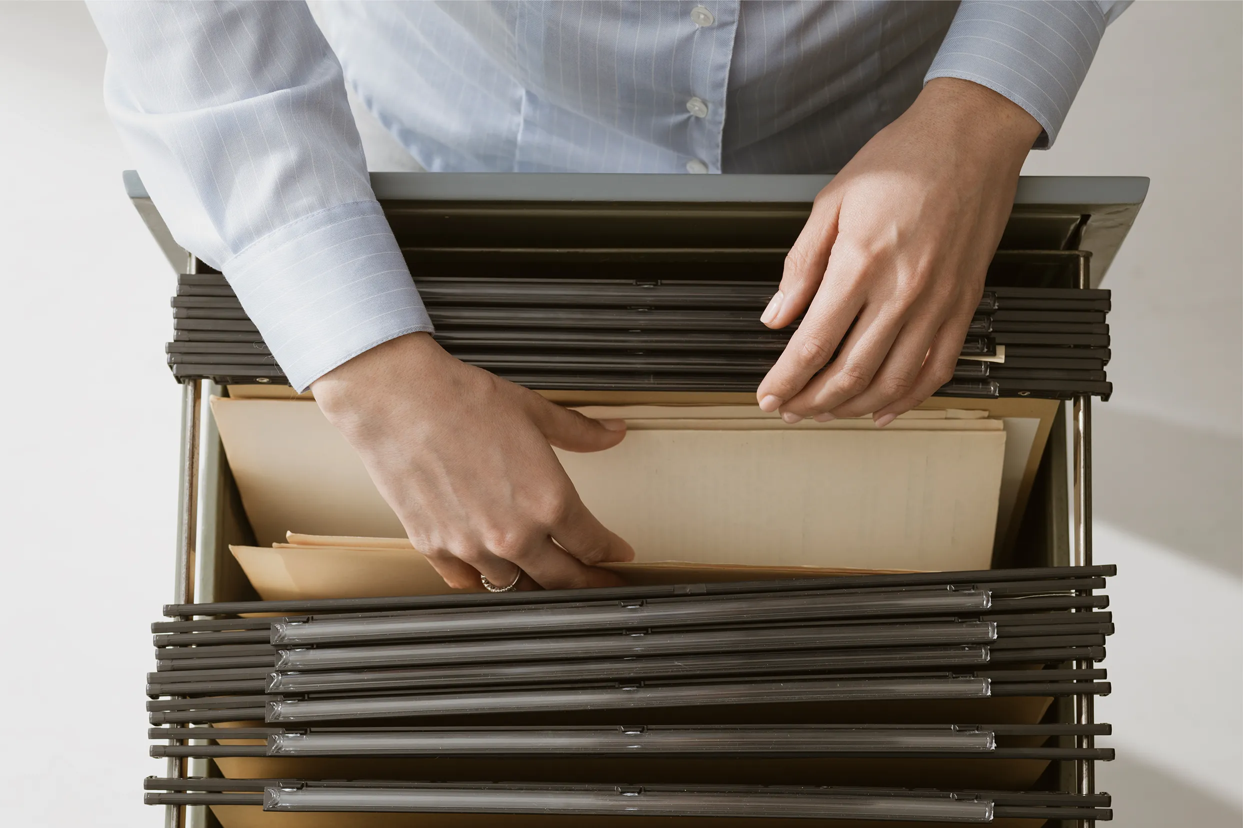 Mani che sfogliano le cartelle di un archivio